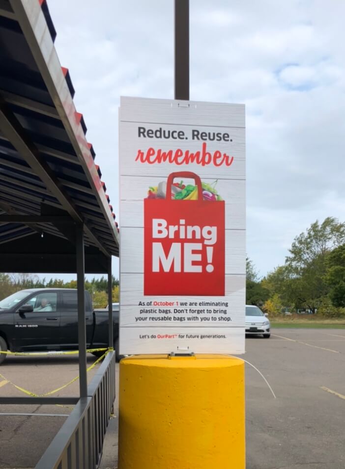A picture of Ourpart holding in parking with text reading: Reduce. Reuse. Remember, Bring me a carry bag.