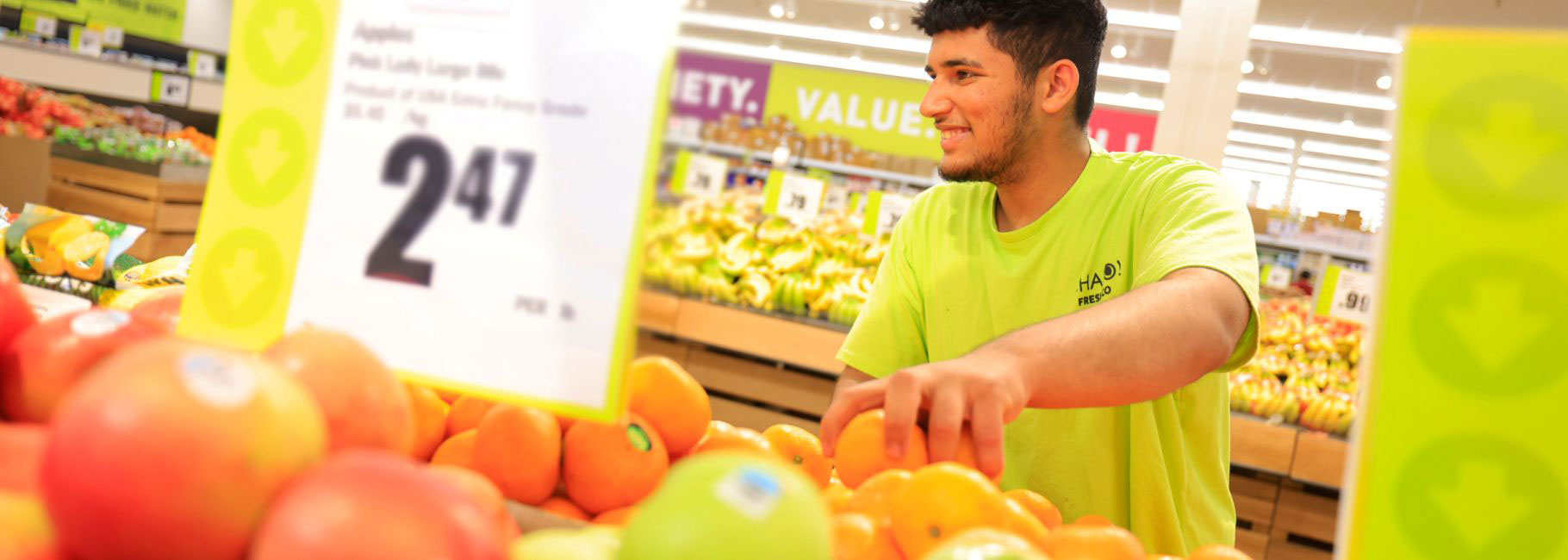 Chalo FreshCo employee stocks fresh fruit in-store.