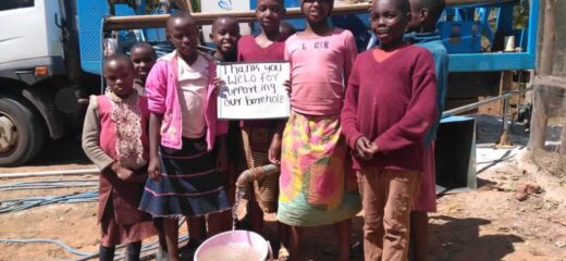 The image shows a group of kids holding a poster and writing on it saying 