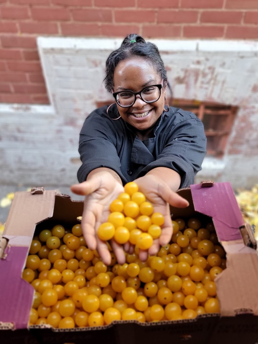 Second Harvest employee in front of their delivery trucks with gooseberries in hands