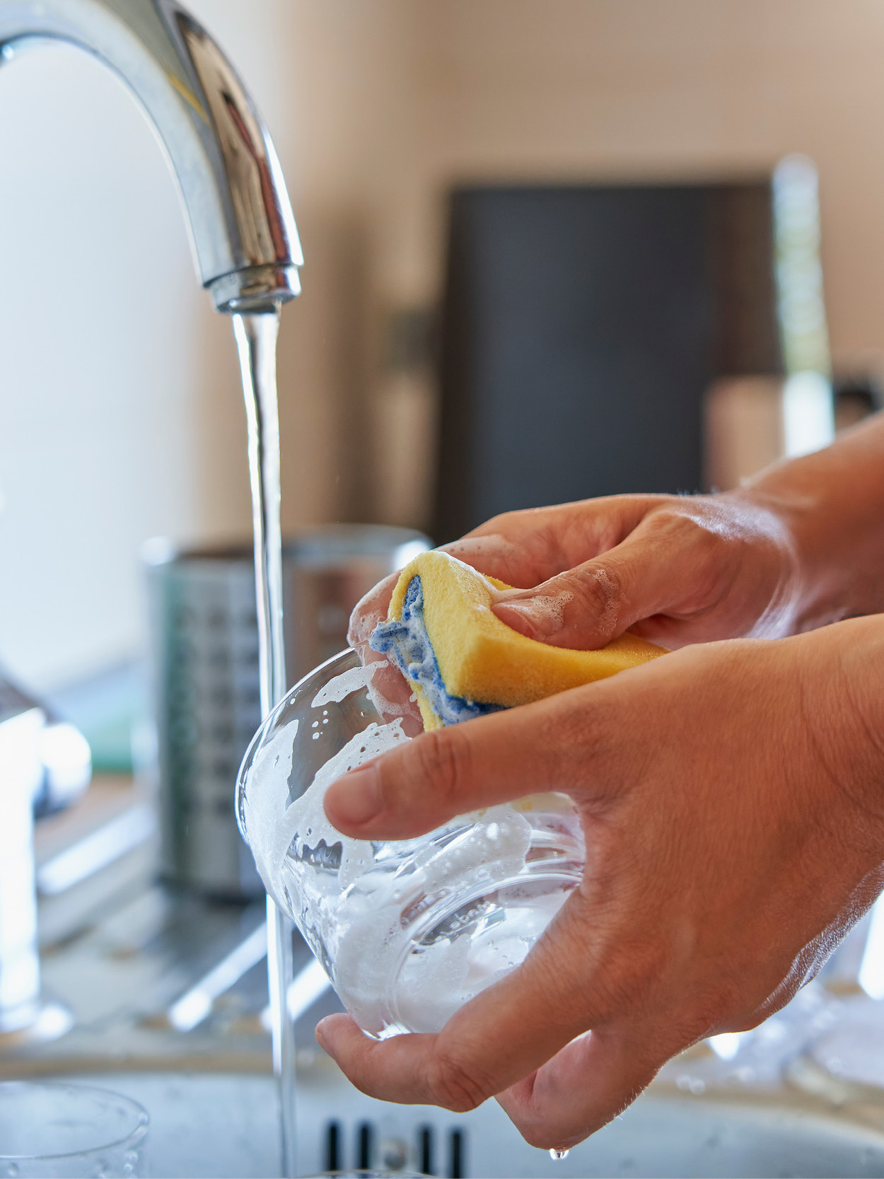 Woman washing glass with a reusable sponge  